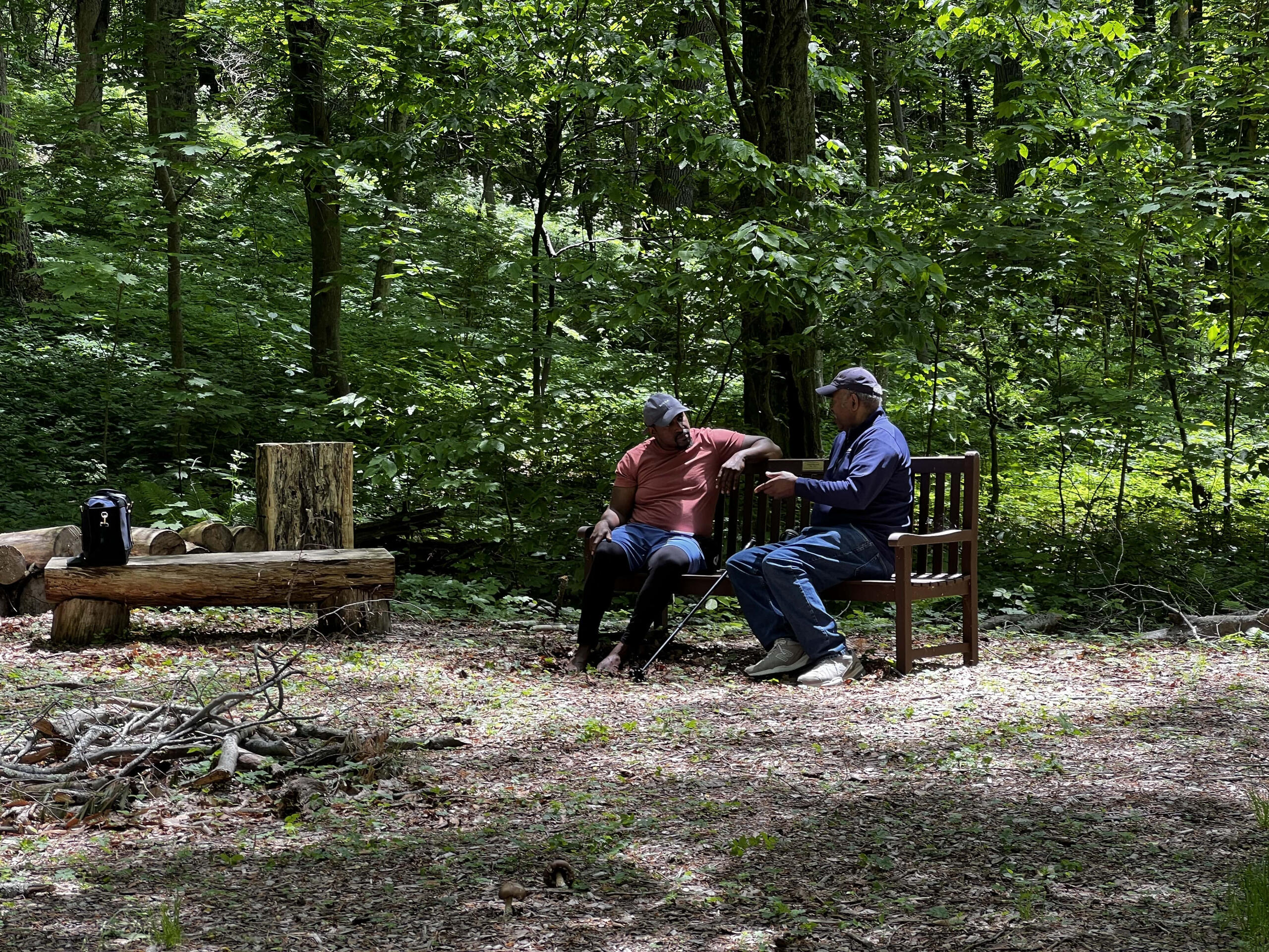 two Black men sit in nature discussing some of their prominent memories with nature together
